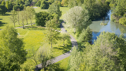 Luftaufnahme der Altmühl durch den Kurpark. In der Ferne laufen zwei Personen auf dem Weg.