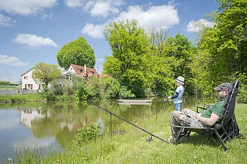 Vater, sitzend, angelt mit kleinen Sohn, stehend, an der Fossa Carolina
