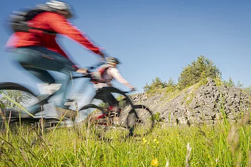 Zwei Fahrradfahrer die Fahrrad fahren und im Hintergrund ist ein kleiner Berg zu sehen