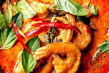 THAI SHRIMPS RED CURRY. Thailand tradition red curry soup with shrimps prawns and coconut milk. Panaeng Curry in blue plate on gray background.