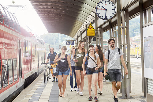 Eine Gruppe junger Erwachsener läuft am Bahnsteig entlang