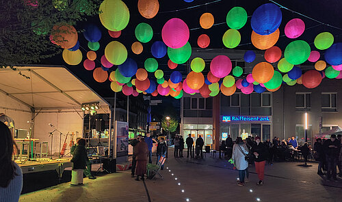 Bunte Lampions schweben über der Bühne am Wallmüllerplatz im Abendlicht