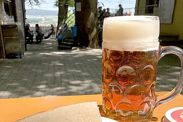 Drei Bratwürste mit Kraut und Brot auf einer Bierbank, dazu eine Maß Wettelsheimer Keller Märzen