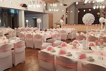 Elegante Dekoration in rosé-weiß, eingedeckt mit Kaffeegeschirr, Stühle überzogen mit Hussen in weiß, dazu Schleifen in rosé