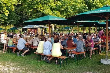 Blick von der Wiese in den Biergarten an der Stadthalle an einem sonnigen Tag.