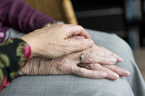 Eine Hand liegt auf der anderen Hand einer älteren Frau
