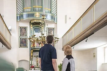 Paar besichtigt Kirche,  Altar und Orgel mit Empore sichtbar