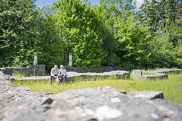 villa rustica mit viel Natur und im Hintergrund ein Paar sitzend auf einer Mauer
