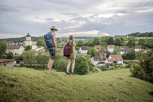 Ein Paar wandert auf dem Gundelsheimer Höhenweg, im Hintergrund das Dorf
