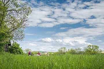 Familie rastet an der Schutzhütte unter blauen Himmel mit Schäfchenwolken