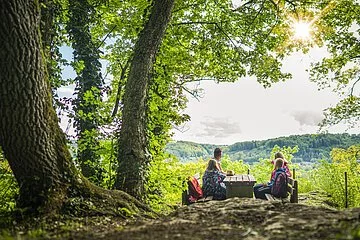 Familie beim rasten auf einer Bank an einem Tisch und genießt den Ausblick.