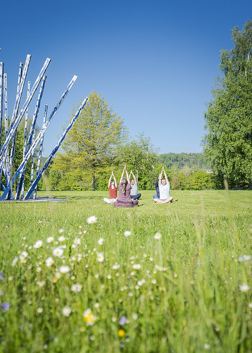 Yoga in der Gruppe im Kurpark mit Arme zum Himmel
