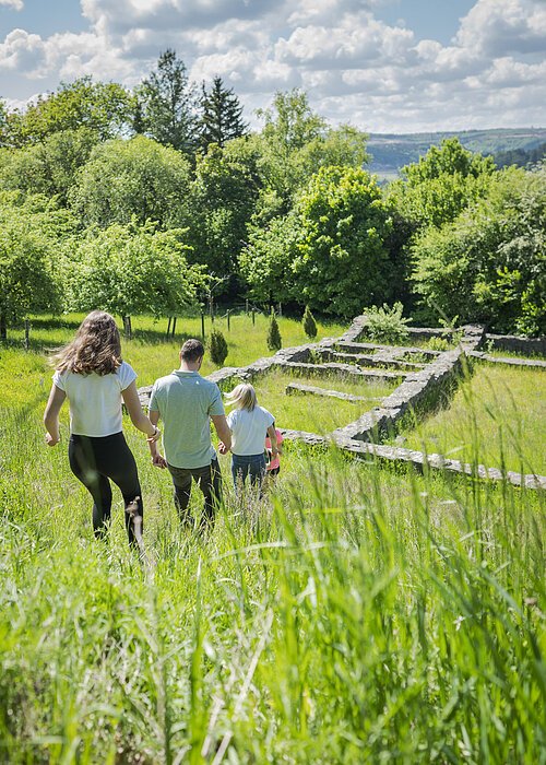 Familie läuft durch die Wiese auf die Villa Rustica zu