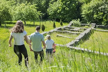 Familie läuft durch die Wiese auf die Villa Rustica zu