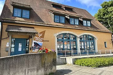 Ein historisches, orangenes Gebäude mit großen, blauen Rundfenstern und Dachgiebeln