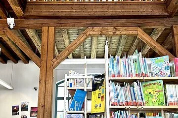 Bücherregale im Erdgeschoss, nach oben öffnet sich das Dachgebälk und ein Holzgeländer