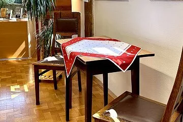 Leseecke mit Tisch und zwei Stühlen vor Fenstern und unter einem Dachgebälk