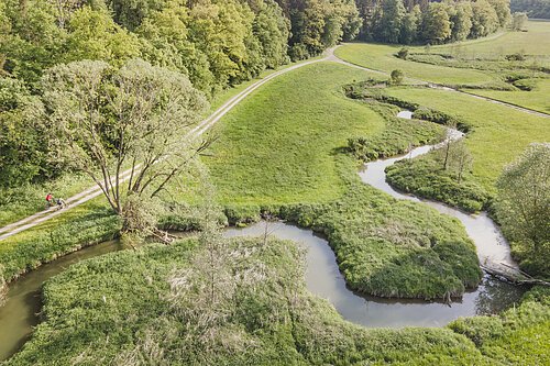 Radfahrer fahren entlang des Möhrenbachs, der Fluss schlängelt sich aus der Vogelperspektive