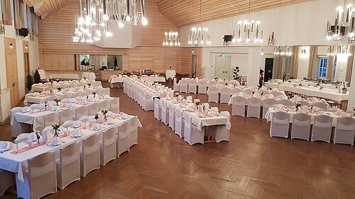 Von oben fotografiert sieht man den kleinen und großen Saal. Die Bestuhlung ist sternförmig angeordnet, das Kalt-Warme Buffet wird im kleinen Saal aufgebaut. Die Trennwand wurde zurückgefahren, damit beide Räume einen großen Saal bilden.