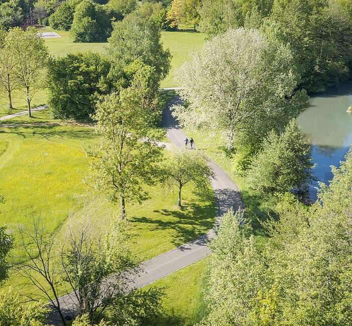 Luftaufnahme der Altmühl durch den Kurpark. In der Ferne laufen zwei Personen auf dem Weg.