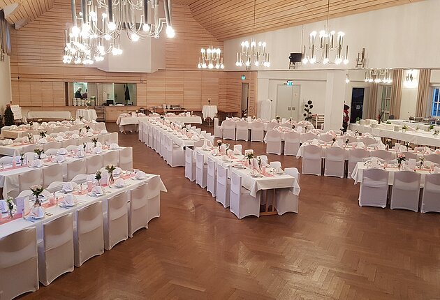 Von oben fotografiert sieht man den kleinen und großen Saal. Die Bestuhlung ist sternförmig angeordnet, das Kalt-Warme Buffet wird im kleinen Saal aufgebaut. Die Trennwand wurde zurückgefahren, damit beide Räume einen großen Saal bilden.