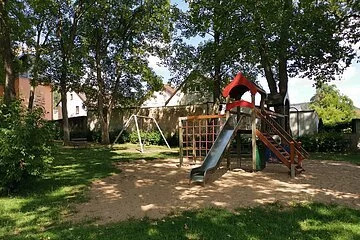 Schattiger Spielplatz mit Rutsche und Schaukel