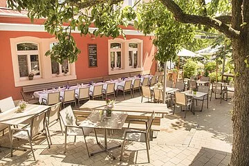 Lauschiger Biergarten unter Bäumen mit Sitzmöglichkeiten