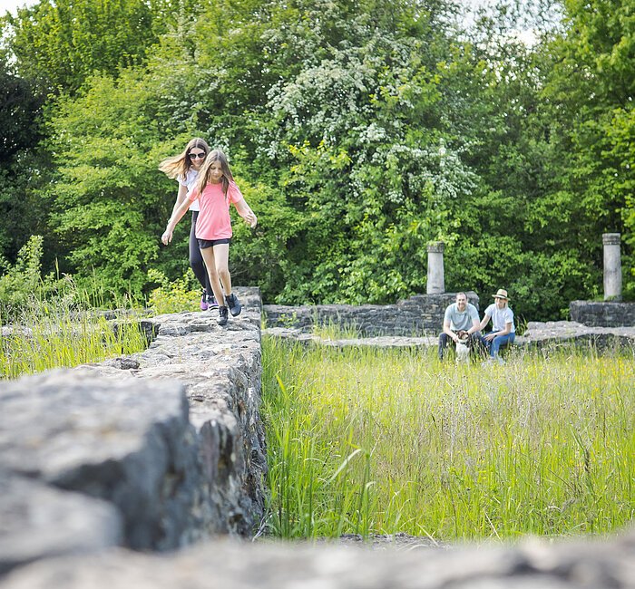 Spielende Kinder an der Villa Rustica und im Hintergrund entspannde Eltern