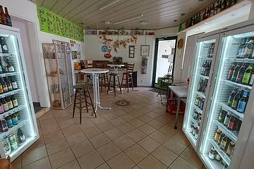 Verkaufsraum von Feine Biere, auf der linken und rechten Seite stehen Kühlschränke mit zahlreichen Biersorten. Im Hintergrund befinden sich Stehtische.