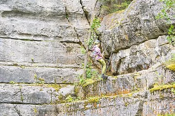 Frontaufnahme eines Kletter-Hangs am Steinbruch Möhren. Ein Kletterer erklimmt mit professioneller Ausrüstung die Steinwand im Hintergrund.
