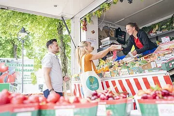 Aufnahme an einem Obst- und Gemüsestand am Treuchtlinger Wochenmarkt. Ein junges Pärchen kauft gerade ein.