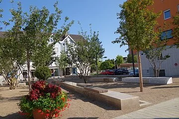 Partnerschaftsplatz mit Sitzbänken aus Stein und Marmor und Bäume.