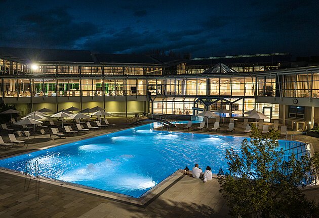 beleuchtetes Außenbecken der Therme bei Nacht