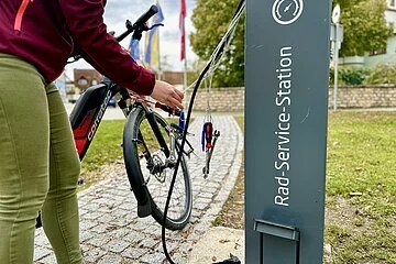 Radfahrerin nutzt Werkzeug und Luftpumpe an der Radservice-Station