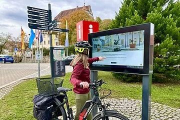 Radfahrerin bedient Infoterminal