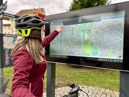 Radfahrerin bedient Inforterminal am Radvervice-Platz