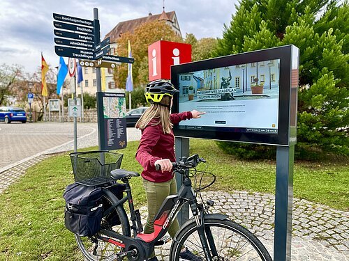 Radfahrerin bedient Infoterminal