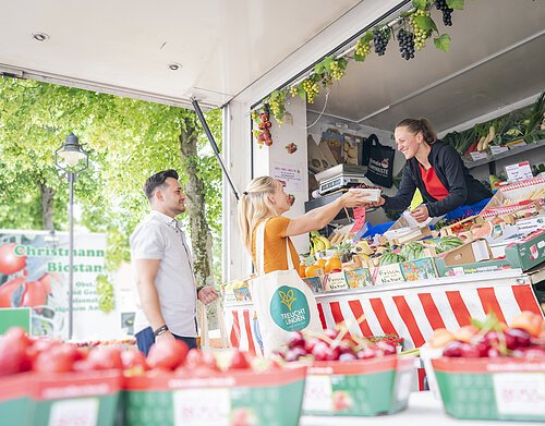 Aufnahme an einem Obst- und Gemüsestand am Treuchtlinger Wochenmarkt. Ein junges Pärchen kauft gerade ein.