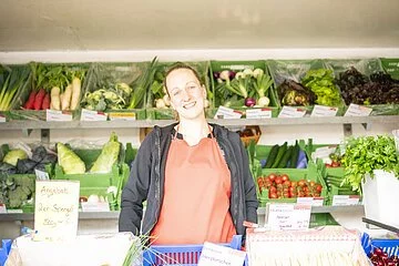Frontaufnahme einer Verkäuferin in einem Obst- und Gemüsestand am Treuchtlinger Wochenmarkt.