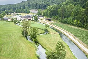 Drohnenaufnahme mit weitem Blick in das Möhrenbachtal. Der Möhrenbach mäandriert wunderschön durch die weiten Felder am Waldrand entlang.