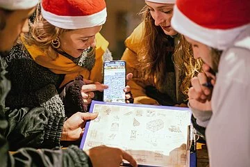 Vier Frauen mit Weihnachtsmützen lösen ein Rätsel