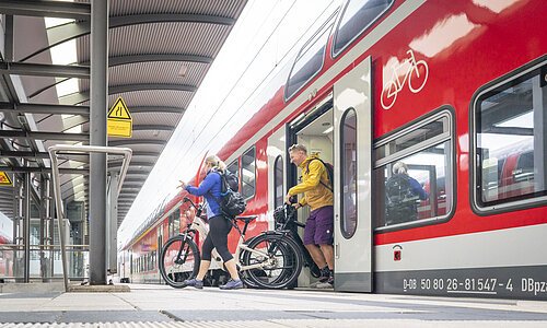 Aufnahme eines Treuchtlinger Bahnsteigs. Ein Regionalzug der Db hält am Gleis. ein Pärchen mit E-Bikes steigt aus dem Zug aus.