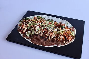 Ein Cigköfte Wrap offen auf schwarzem Teller