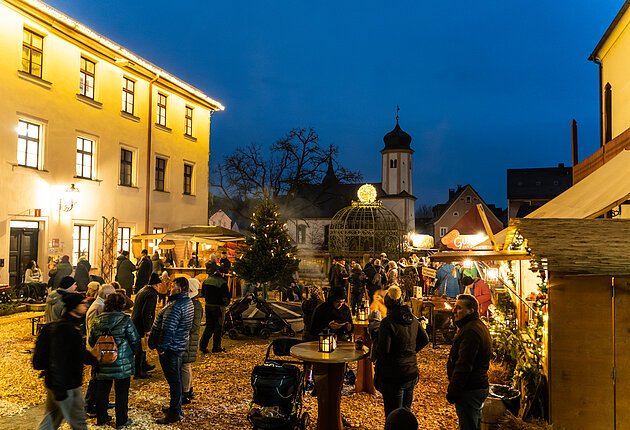 Der Schlosshof mit Hackschnitzeln ausgelegt, rechts stehen Marktbuden, in der Mitte versammeln sich die Besucher