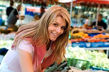 Junge Frau beim Gemuesestand am Markt