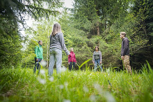 Teilnehmer stehen im Kreis auf einer Lichtung im Wald