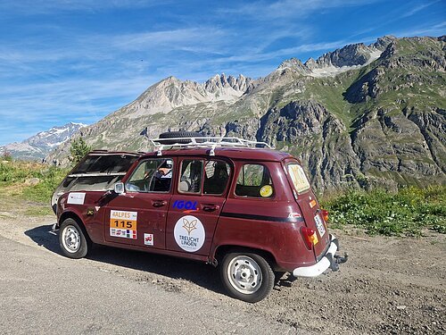 Auf dem Bild ist ein Auto in einer Gebirgslandschaft zu sehen. Das Auto ist beklebt mit verschiedenen Aufklebern.