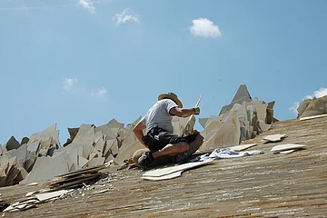 Ein Dachdecker legt die Juraplatten auf den Dachstuhl eines Jurahauses