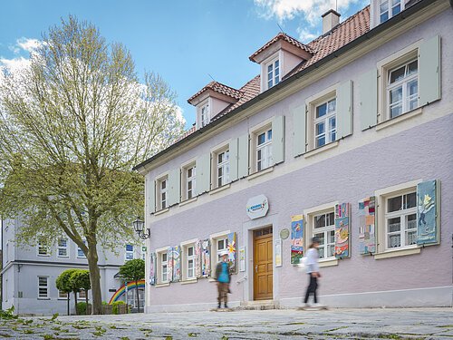 Bürgerhaus, Vorderseite mit umhäkelten Fensterläden, junge Skater fahren daran vorbei, im Vordergrund Kopfsteinpflaster