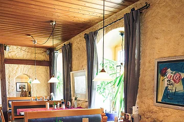 Teil des Gastraums durch Balken abgetrennt vom Hauptraum, Hochtische mit Bänken